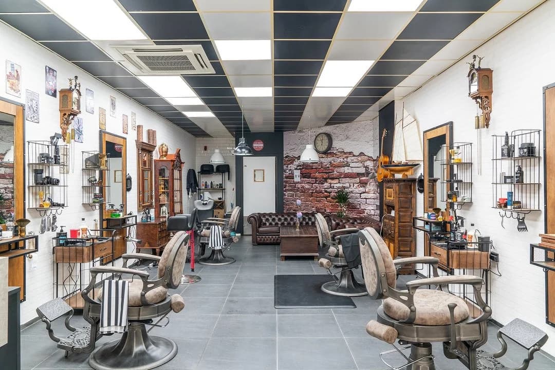 Het interieur van Pacino Zoetermeer met klassieke barberstoelen en een leren bank